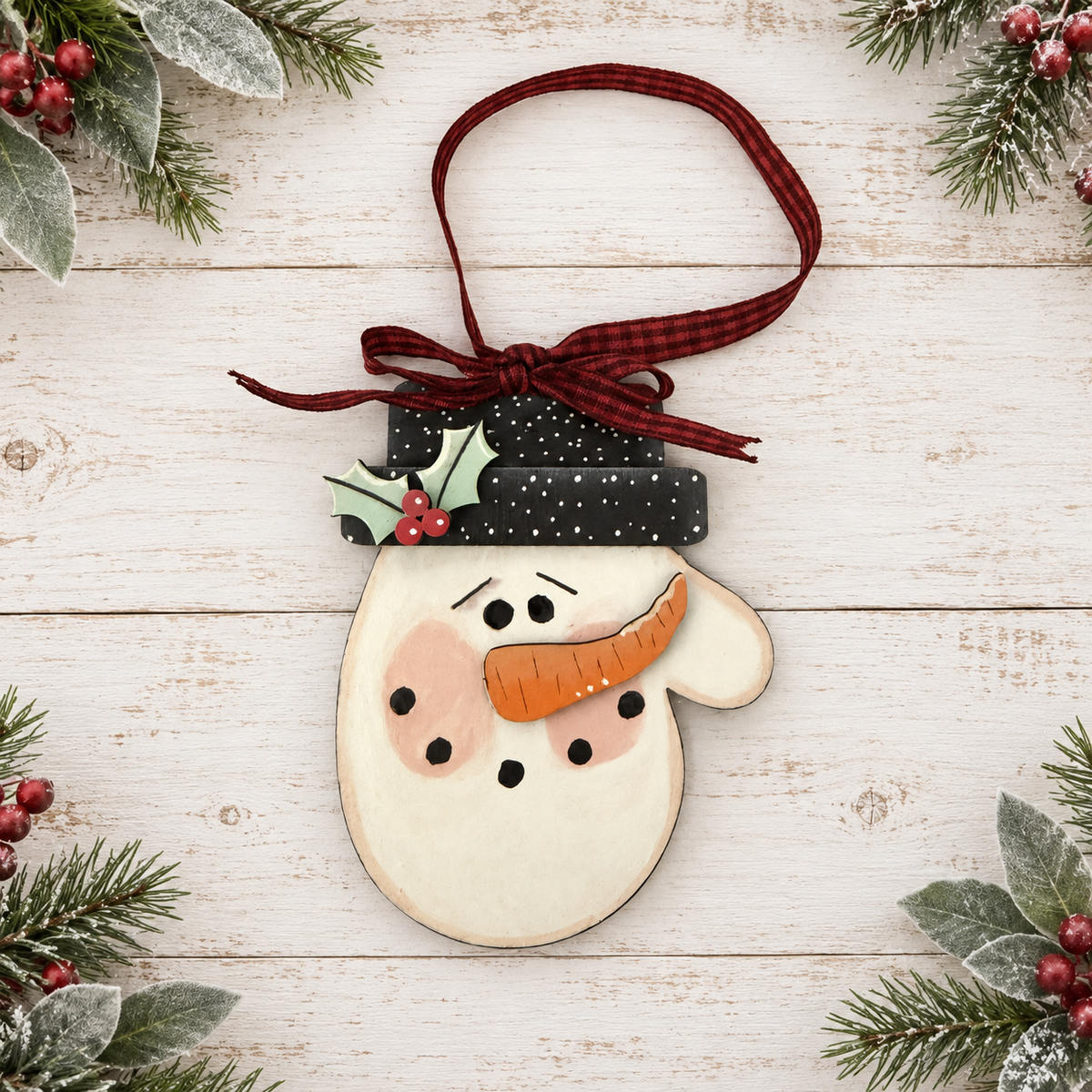 Whimsical hand-painted snowman face ornament with black top hat and burgundy plaid ribbon